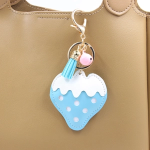 Détail d'un porte-clés fraise en cuir PU bleu clair avec pompon et clochette sur sac