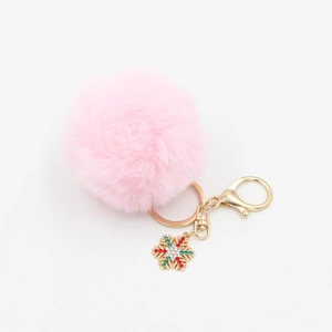 Close-up of pink faux fur pompom keychain with golden metal ring and rhinestone snowflake