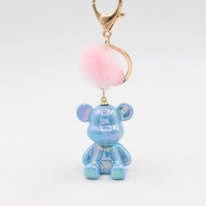 Detailed macro view of iridescent blue resin bear keychain with a soft pink plush pompom