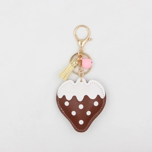Détail d'un porte-clés fraise en cuir avec pompon, fermoir doré et petite clochette rose
