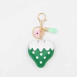 Détail du porte-clés fraise avec clochette rose, gland vert clair et fermoir doré chic