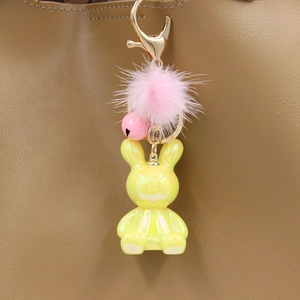 Iridescent yellow bunny keychain with pink fur pom pom detail on a brown leather bag