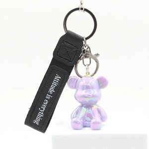 Detail of a purple iridescent bear keychain with Attitude is everything wrist strap