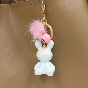 Detail of resin rabbit keychain with mink fur ball and bell on a leather handbag