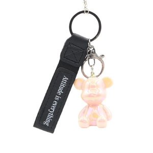 Pink cartoon bear keychain with black leather strap and metal ring on white background
