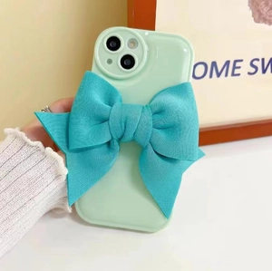 Detail of light green phone case with large blue fabric bow accessory for iPhone