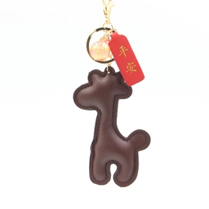 Porte-clés girafe en cuir marron avec anneau doré et breloque perle orange sur fond blanc