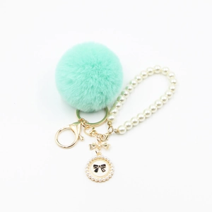 Mint green pompom keychain with pearl chain and bow charm on white background