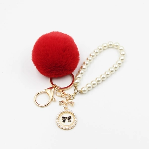 Red pompom keychain with pearl strap and golden bow charm for bags and car keys