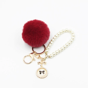 Elegant burgundy pompom keychain with white pearl chain and golden bow charm for handbag