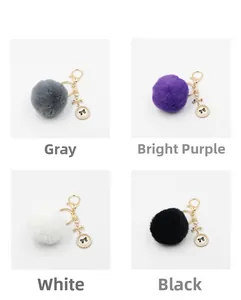 Close-up of plush pompom keychain showing gray, purple, white, and black color options