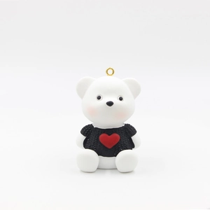 Close-up of white resin bear charm wearing a black heart sweater with gold keychain
