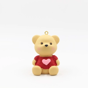 Detail of a beige bear figurine wearing a red knitted sweater with a pink heart pendant