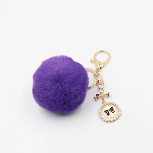 Detail view of purple faux fur keychain with golden lobster clasp and pearl bow charm