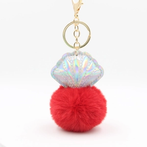 Detail of laser shell charm with a vibrant red faux fur pompom and gold metal clasp