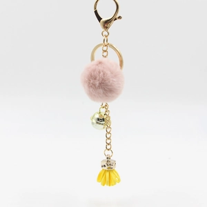 Dettaglio del pompon rosa con campanellino dorato e nappa gialla per portachiavi borsa
