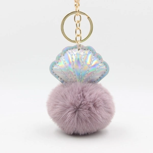 Detail of laser seashell pendant with purple faux fur pompom and golden metal keychain