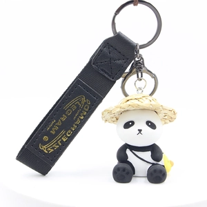 Detail of panda charm with straw hat and yellow duck bag on black woven strap