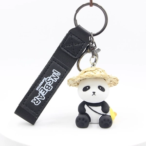 Detail of panda keychain with straw hat, mini duck bag, and black woven strap accessory