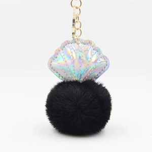 Detailed view of holographic shell pendant with soft black pom pom and gold keychain hook