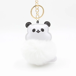 Close-up of cute panda plush pom-pom keychain with gold metal ring and soft faux fur