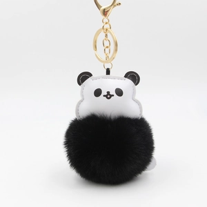 Close-up of fluffy black pom pom panda keychain with gold lobster clasp and white leather head