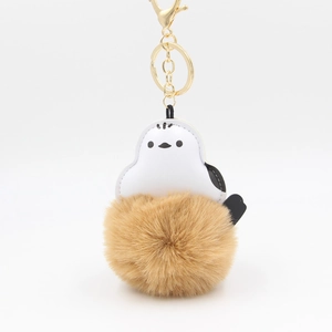 Detailed view of white bird leather charm with fluffy brown fur pompom and gold clasp