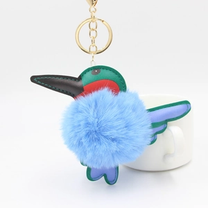 Detail of colorful faux leather hummingbird keychain with a soft blue plush ball and gold ring