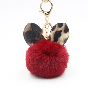 Close-up of fluffy red plush ball keychain featuring stylish leopard print ears and gold clasp