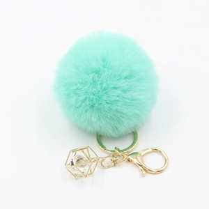 Detail of mint green faux fur pompom keychain with golden lobster clasp and crystal cage