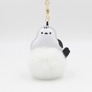 Detail of white penguin plush keychain with soft faux fur pompom and golden metal ring