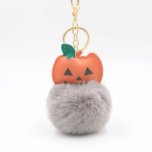 Halloween pumpkin keychain with gray plush pom-pom and gold metal clasp on white background