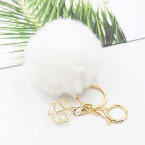 Detail of white fluffy faux fur pompom keychain with golden lobster clasp and crystal pendant