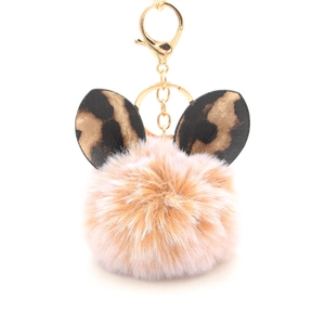 Detail of pink plush pompom keychain with leopard print cat ears and gold hardware