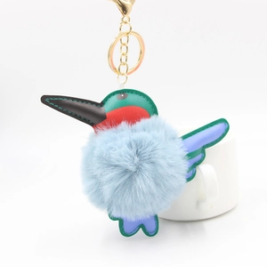 Detail of kingfisher plush pompom keychain with colorful leather patches and gold clip