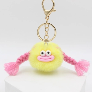 Cute yellow plush monster keychain with pink sausage lips and braided hair on white stand