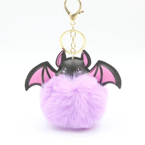 Colorful bat pom-pom keychain with faux fur ball and gold metal ring in pink and purple
