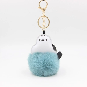 Macro shot of fluffy blue faux fur bird keychain with high-quality gold metal clasp