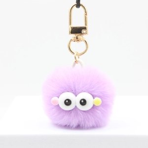 Detail of purple plush fuzzy ball keychain with big cartoon eyes and golden hook