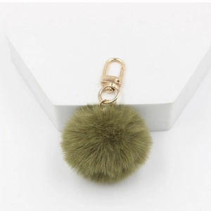 Macro shot of a grass green 4cm fluffy faux fur pompom keychain with gold metal clasp