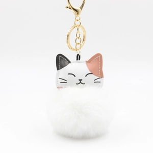 Close-up of fluffy white pompom keychain with a cute tri-color leather cat head and gold clip