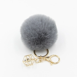 Detailed view of dark grey faux fur pompom with golden lobster clasp and crystal pendant