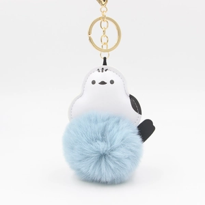 Detail of penguin plush keychain with light blue pom-pom and golden metal ring