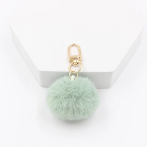 Detail of 4cm mint green faux fur pom pom keychain with gold lobster clasp on white stand