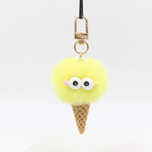 Detail of yellow plush ice cream keychain with cartoon eyes and gold lobster clasp