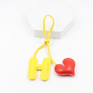 Detail of yellow letter H and red heart PU leather keychain with fine stitching detail