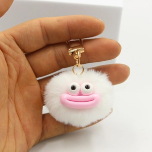 Close-up of white fluffy plush ball keychain featuring a funny pink lip expression