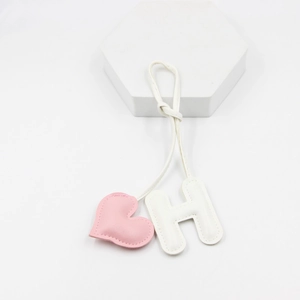 Close-up of pink heart and white letter H PU leather keychain charm with fine stitching