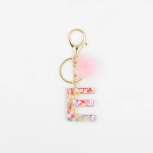 Détail du porte-clés lettre E en résine avec paillettes et pompon rose en fausse fourrure