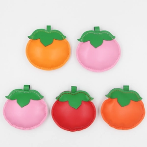 Detailed view of colorful PU leather persimmon pendants with neat stitching and green leaves